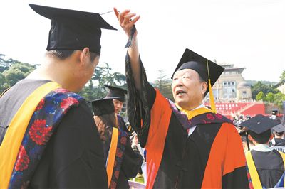 2017年6月22日,李德仁(右一)参加武汉大学毕业典礼并为毕业生拨穗。